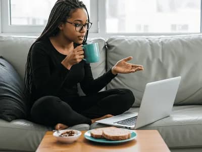 A professional, cross-legged on a cozy gray couch, appears to be conducting an ADHD consultation or explanation while sipping from a turquoise mug